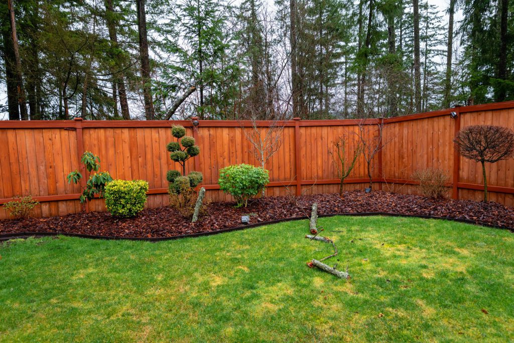 Professional applying cedar fence stain with the wood grain