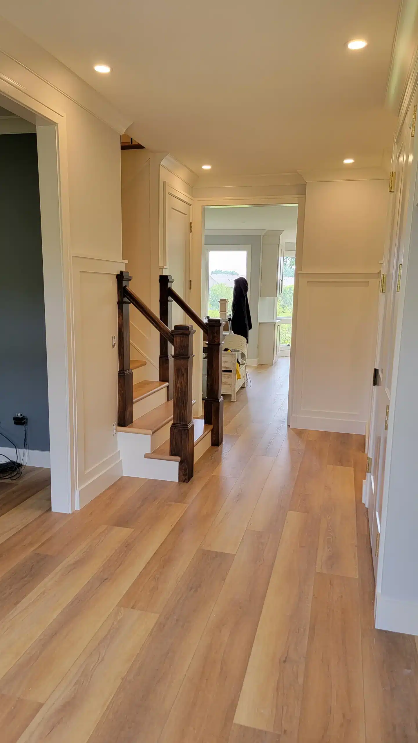 Professional Interior Painting for Hallways and Staircases Bright residential hallway with freshly painted light walls, white trim, and a dark wood staircase, showcasing interior painting.