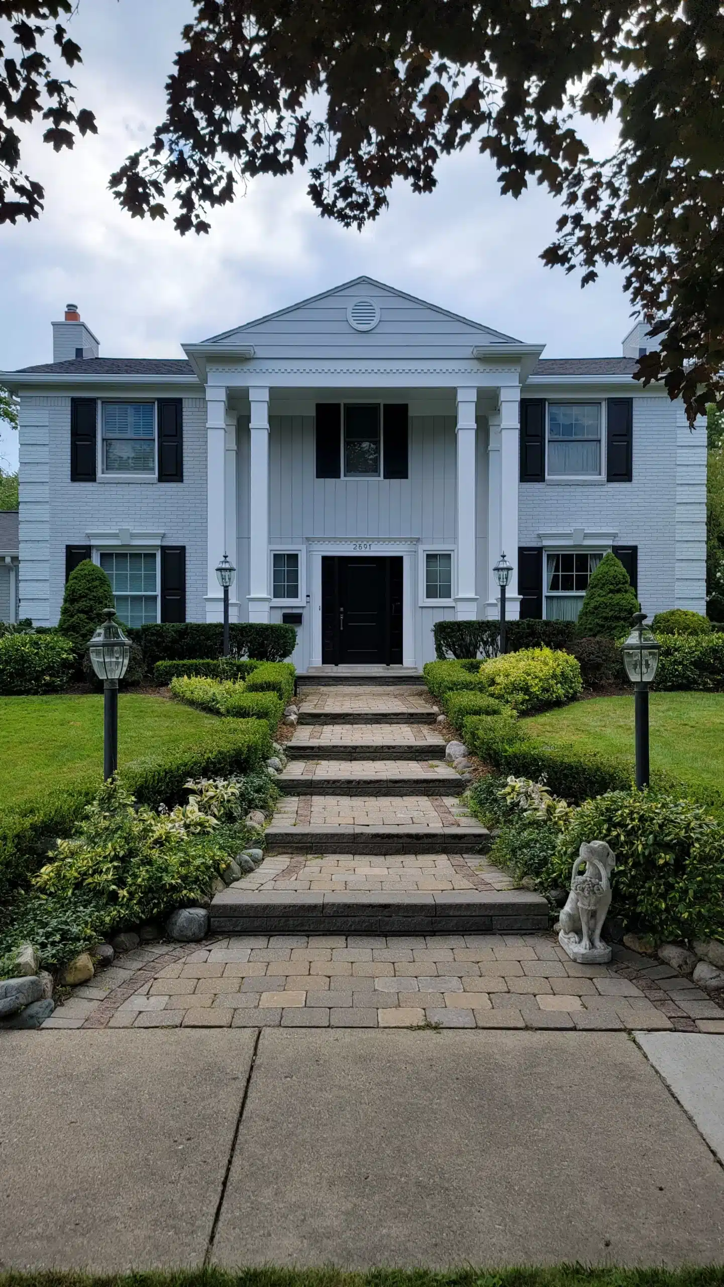 Elegant White Colonial House Exterior Painting A stately white colonial house with black shutters and a grand entrance, showcasing professional exterior painting.