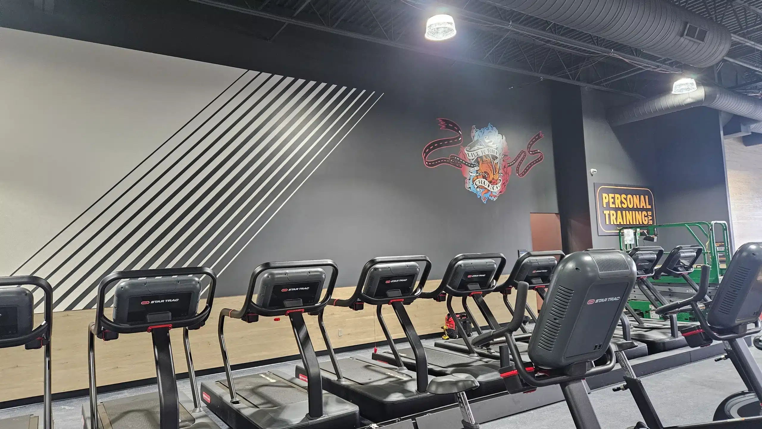 Gym Interior Painting and Graphic Design in Plymouth Michigan Modern gym interior with a gray wall, black striped graphic, and company logo, showcasing commercial painting in Plymouth, Michigan.