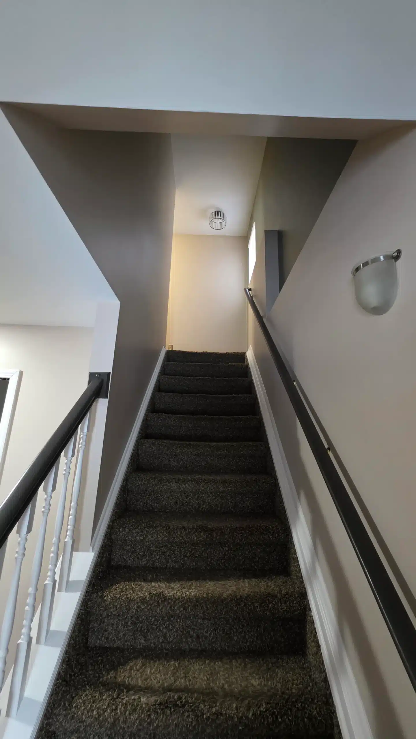 Staircase and Hallway Interior Painting Residential carpeted staircase with freshly painted light beige walls, leading up to an upper floor, showcasing interior painting.