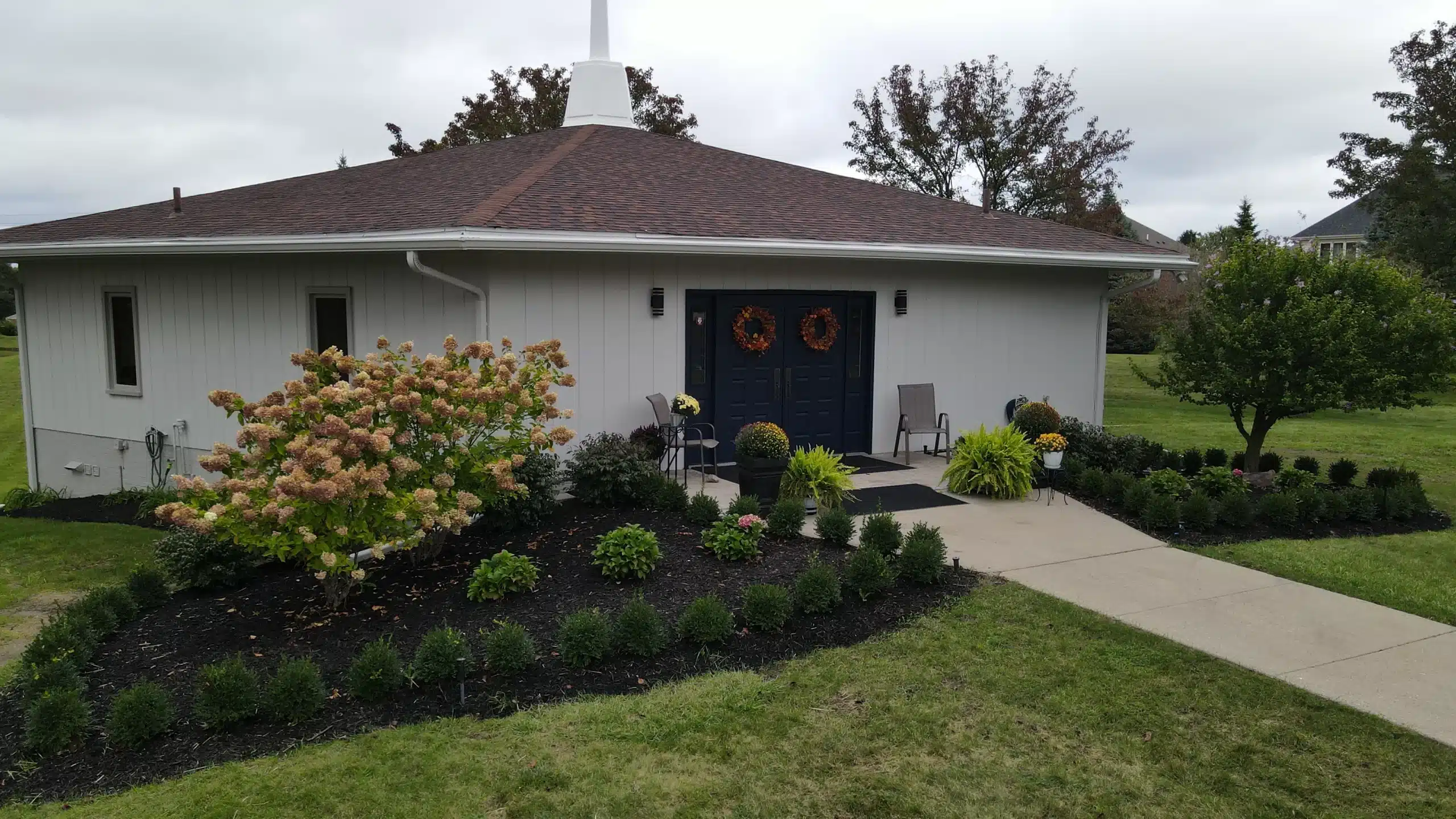 Exterior Painting for Commercial Buildings Freshly painted white exterior of a modern commercial building with dark blue doors and landscaping in Michigan.