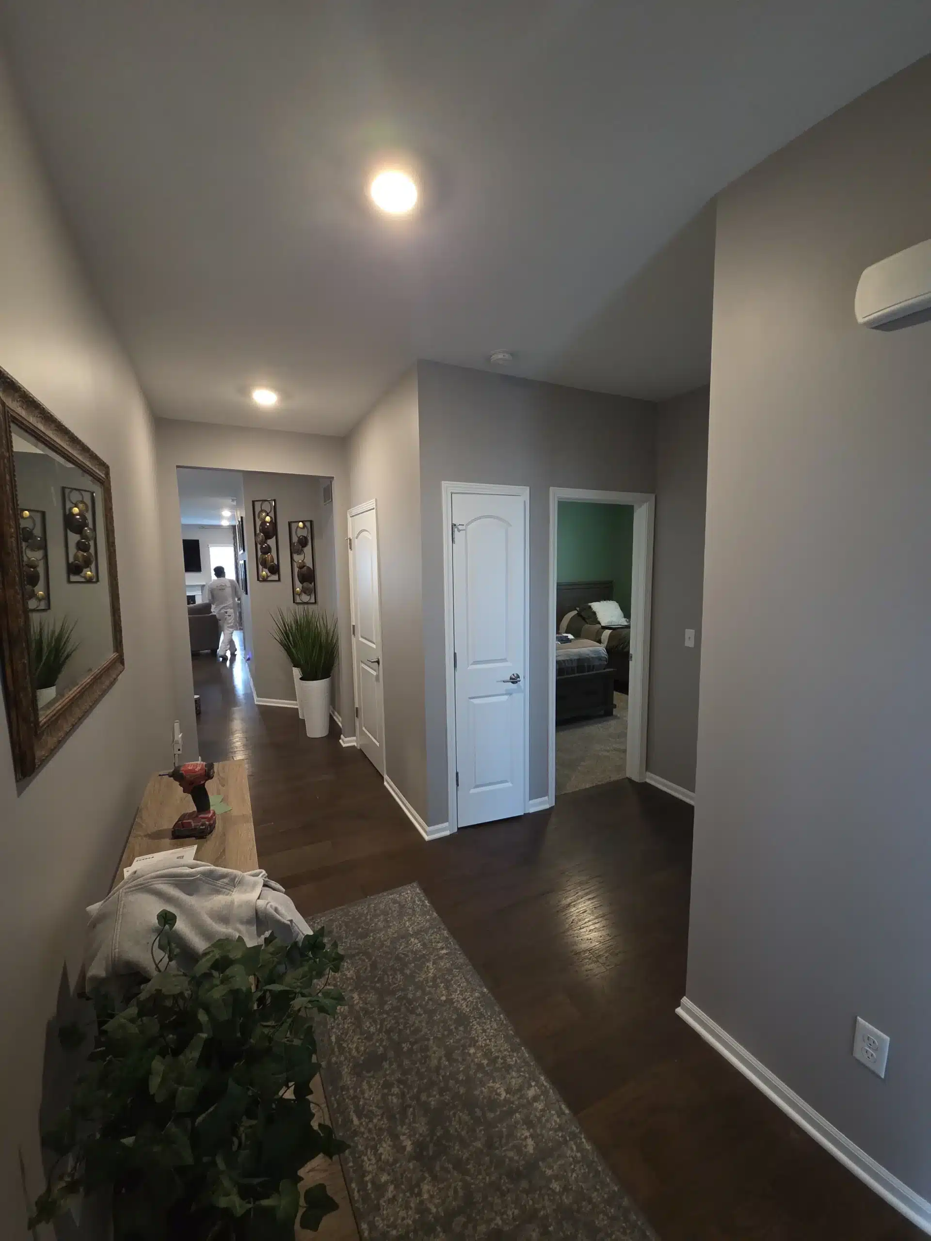 Residential Hallway Interior Painting Project A residential hallway with newly painted light gray walls, dark wood floors, and doors, showcasing professional interior house painting.