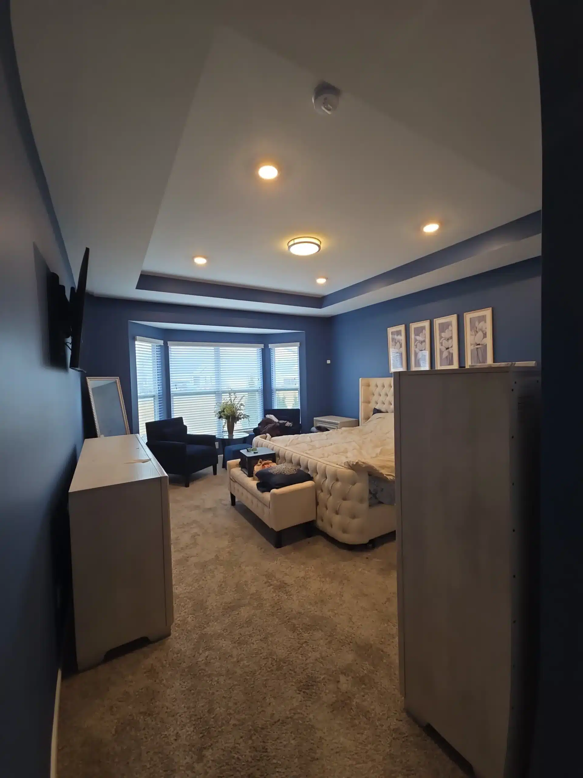 Master Bedroom Interior Painting with Blue Walls and Tray Ceiling Professionally painted master bedroom featuring deep blue walls, a light tray ceiling, and elegant furnishings.